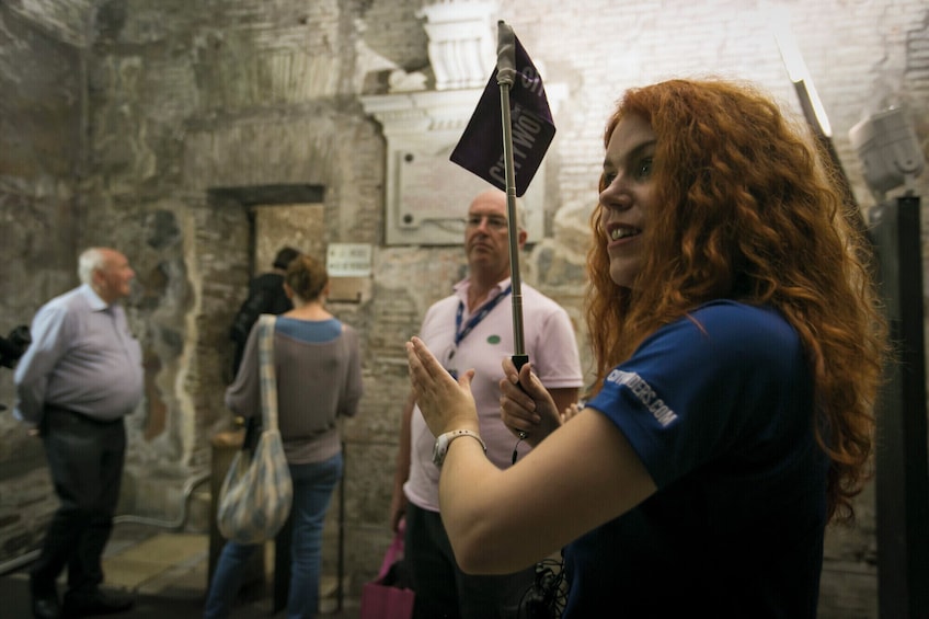 A person holding a flag with 'W' on it, standing in a historical building with stone walls. 4