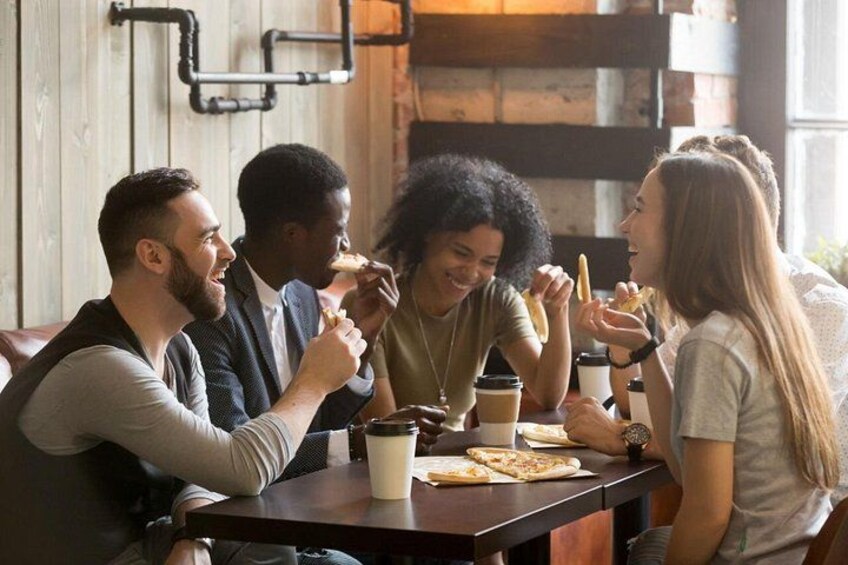 A group of people sitting at a table in a cafe, eating and drinking. 5