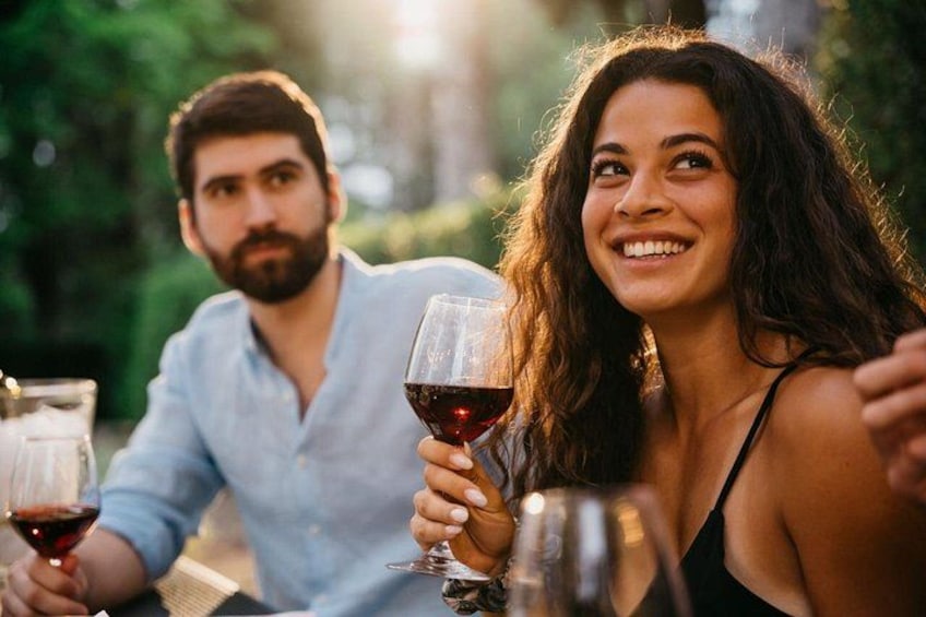 Two people sitting outdoors, holding wine glasses. 1