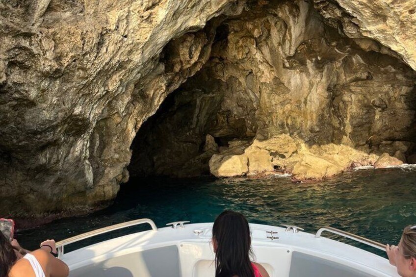 A boat navigating through a rocky cave entrance with clear water. 4