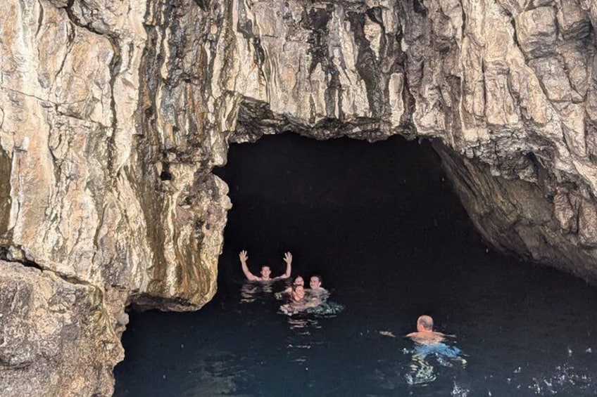 A cave entrance with people swimming inside. 3