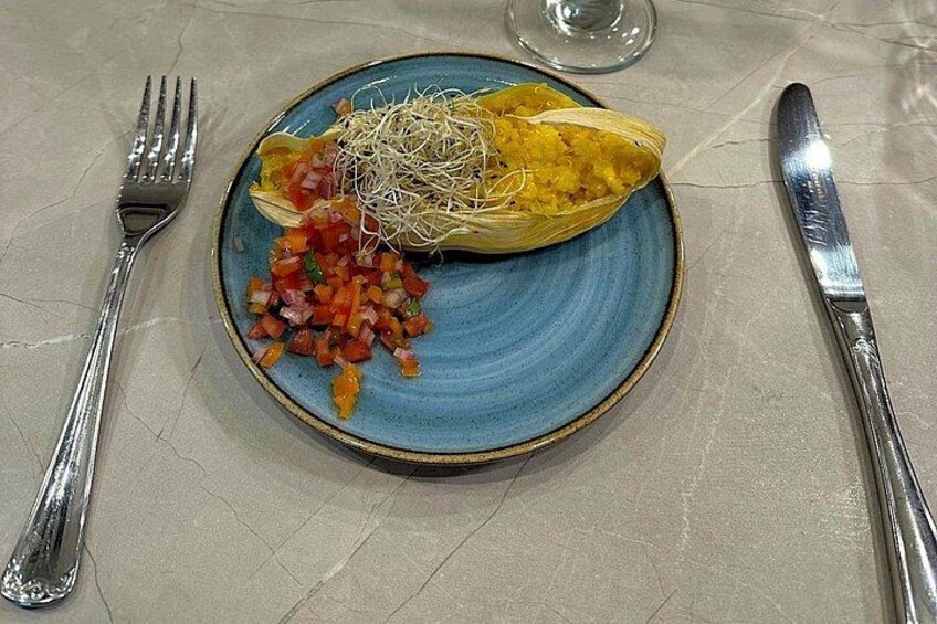 Une assiette contenant un légume farci, une petite salade et un verre d’eau, le tout posé sur une table. 4