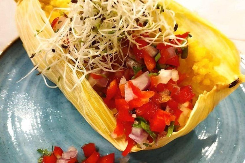 Elote cubierto con una mezcla colorida de vegetales y brotes sobre un plato azul. 4