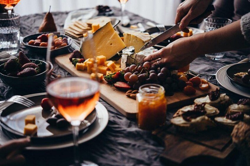 A cheese board with various cheeses, grapes, and nuts on a table. 3