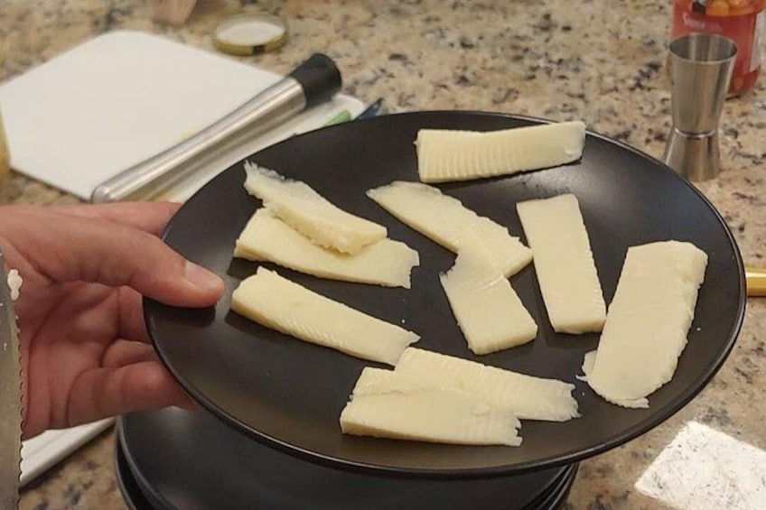 A hand holding a black frying pan with several pieces of food being cooked on a stove. 2