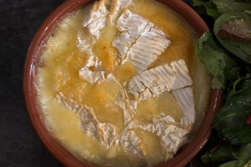 A bowl of soup with fish pieces and a side of greens. 4