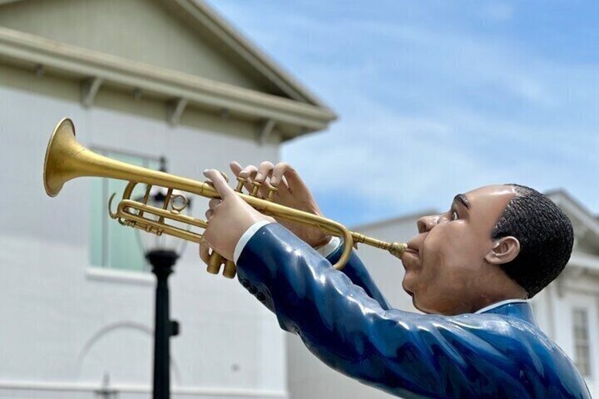 Una persona tocando una trompeta frente a un edificio. 3