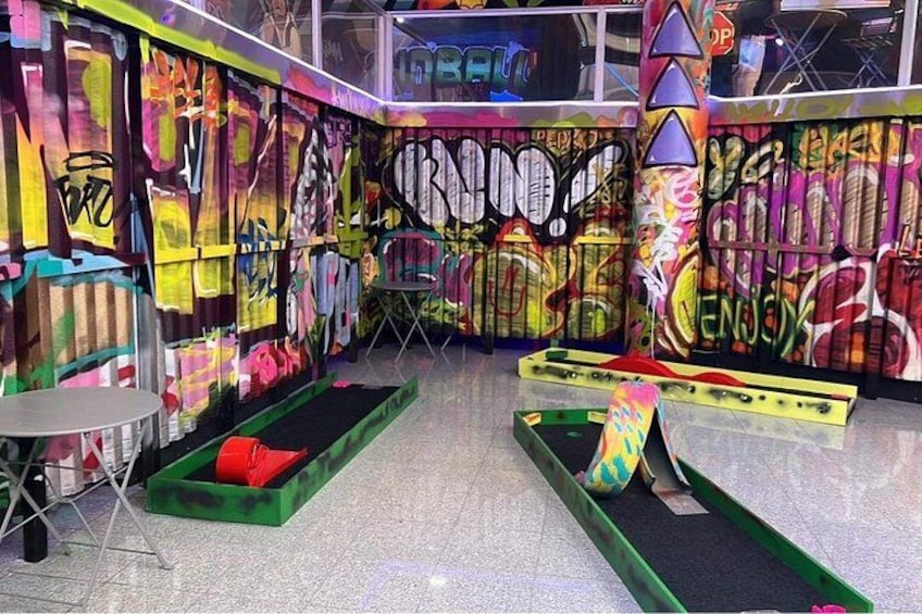 Un espace intérieur dont les murs sont recouverts de graffitis, avec un banc vert et une petite table. 1