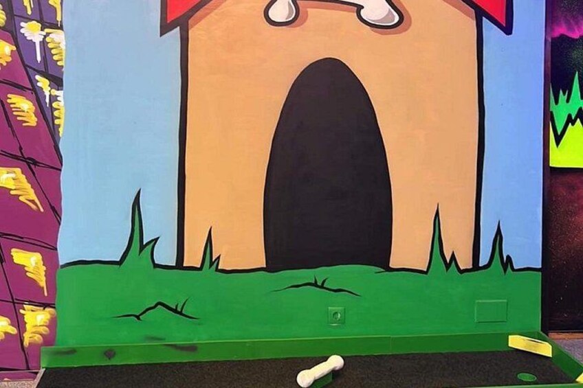 Une fresque colorée représentant une maison avec une grande porte d’entrée en arc de cercle, de l’herbe et une petite fenêtre carrée. 2