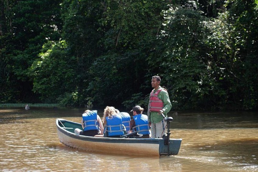 A boat with three people wearing life jackets on a river surrounded by dense greenery. 5