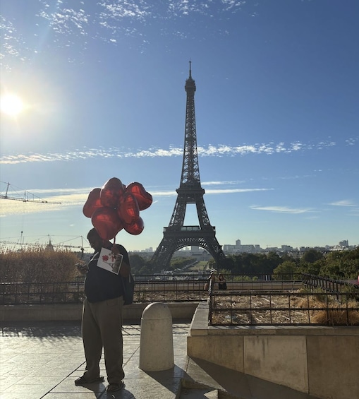 Una persona sosteniendo globos rojos, con la Torre Eiffel al fondo. 3
