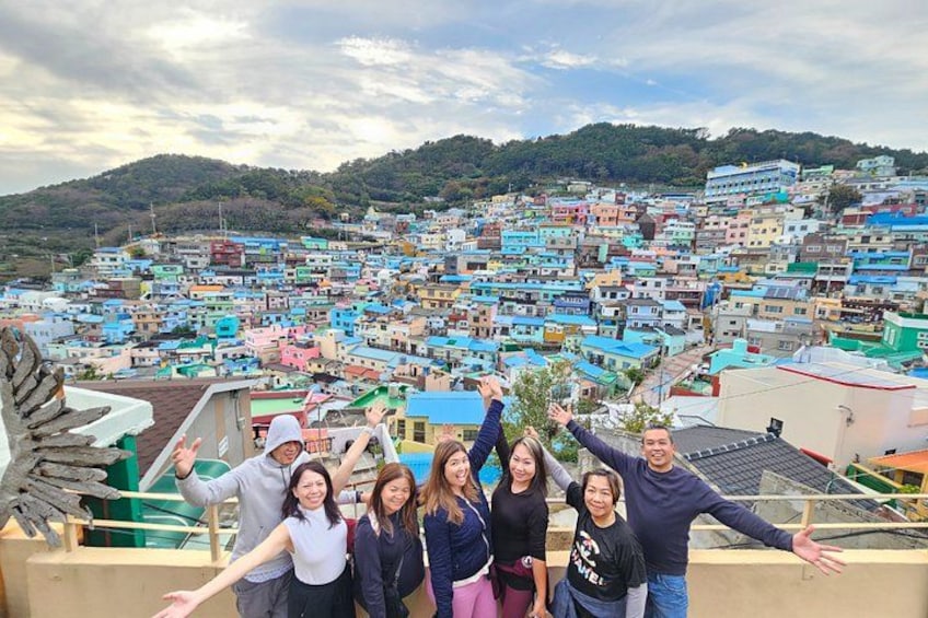 A group of people on a balcony overlooking a densely packed hillside town with colorful buildings. 3