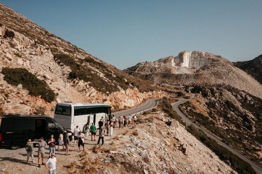 A winding road on a rocky hillside with a bus and people. 2
