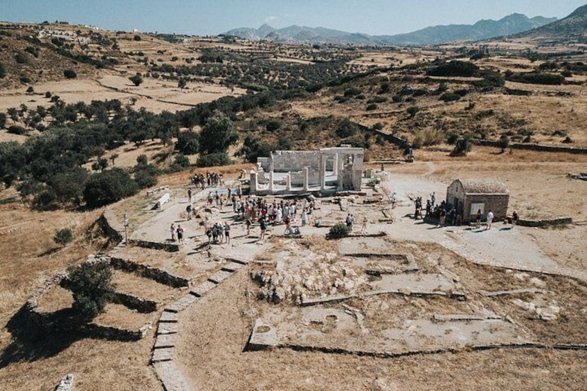 Un sitio arqueológico con ruinas, visitantes y montañas al fondo. 3