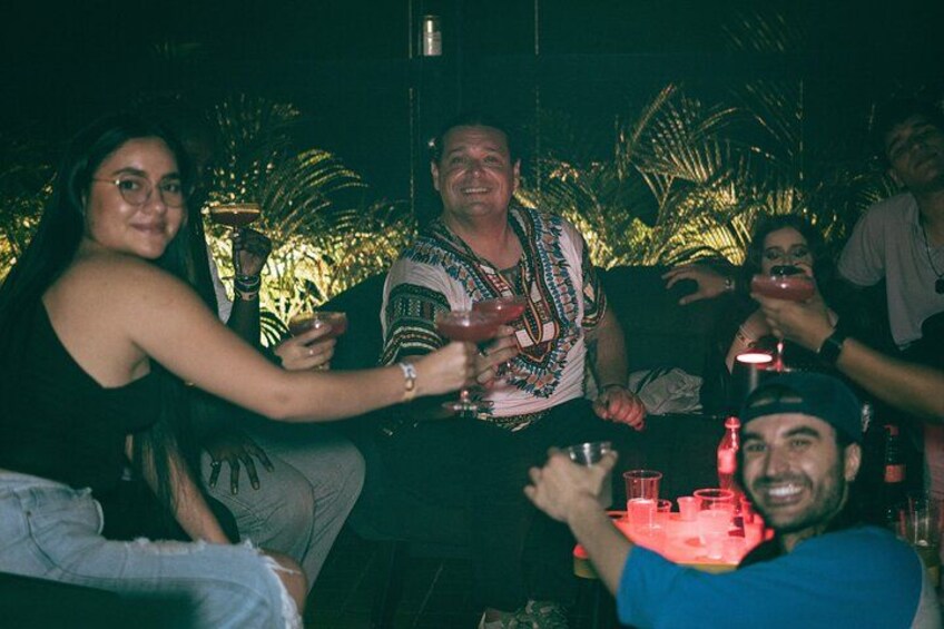 Un grupo de personas brindando con bebidas en un ambiente exterior con poca luz. 4