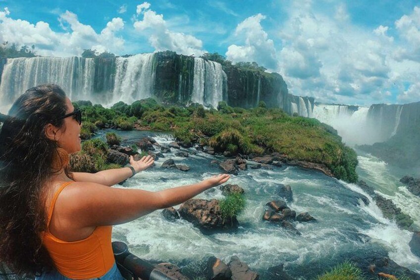 A waterfall with multiple tiers, lush greenery, and a person observing the scene. 1