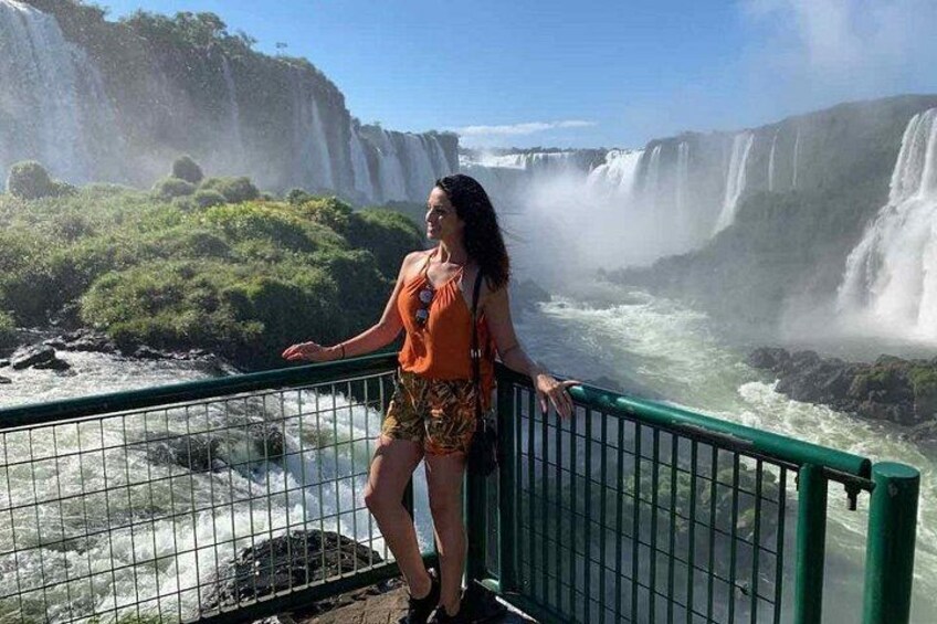 A person standing by a railing overlooking a waterfall. 4
