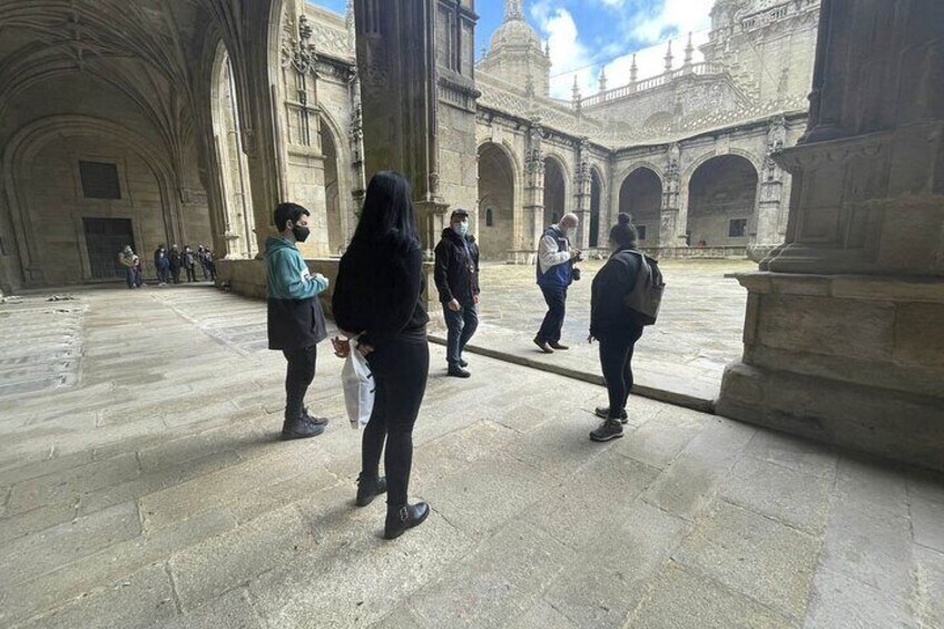 Un groupe de personnes se promène dans une cour caractérisée par son architecture en pierre et ses arcades. 3
