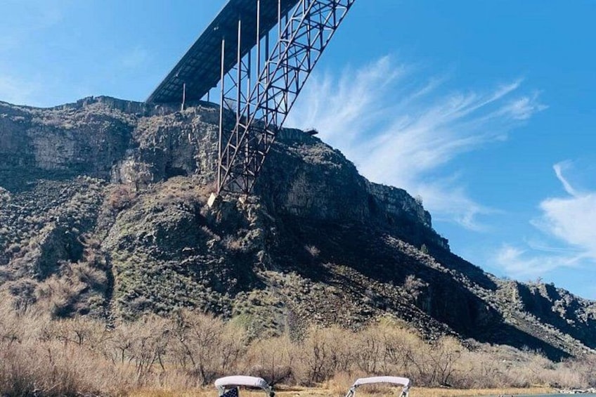 A bridge with a metal framework, a mountainous landscape, and dry vegetation. 2