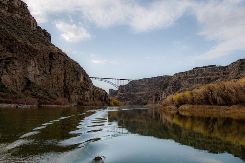 A river with a bridge, rocky cliffs, and autumn foliage. 4