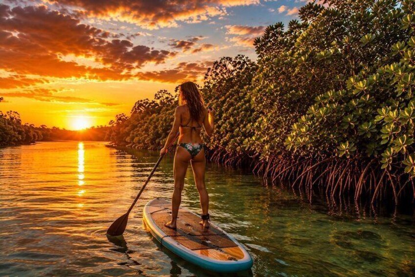 A person paddleboarding on a calm river at sunset. 4