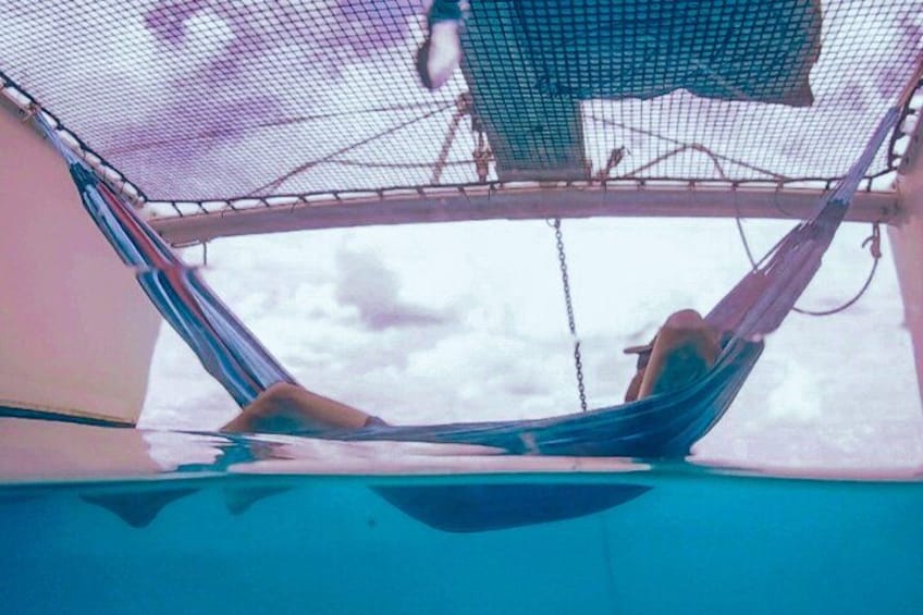 Un hamac est attaché à la rambarde d’un bateau, et une personne est allongée dedans. 2