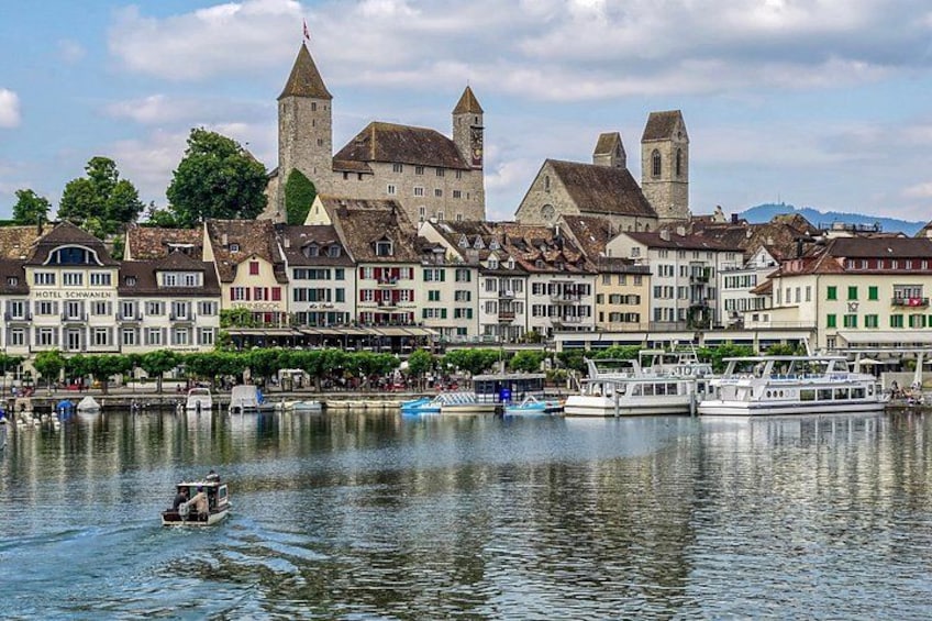 A historic town with a castle, boats on the water, and traditional buildings. 1