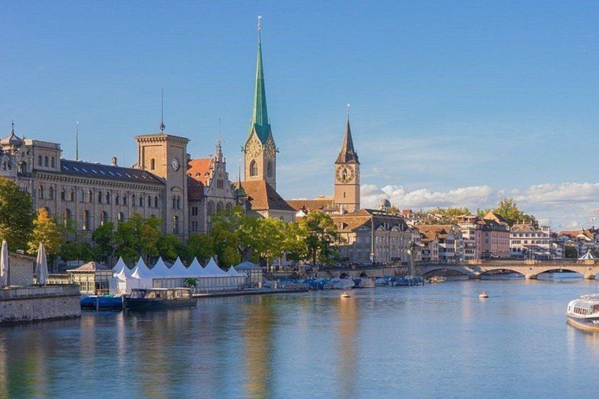 A riverside cityscape with historic buildings, a prominent church spire, and a bridge. 4