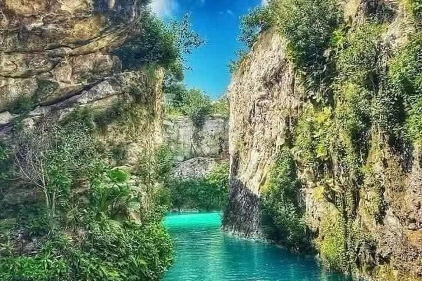 Een turquoise rivier die door een rotsachtige kloof stroomt, met weelderige begroeiing langs de oevers. 5