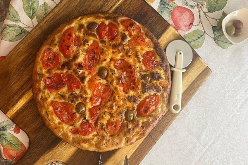 Une pizza sur une planche en bois, avec un coupe-pizza à côté. 2