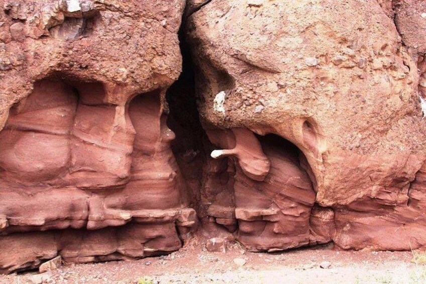 A close-up of layered red rock formations with visible striations and a small white object embedded in the rock. 5