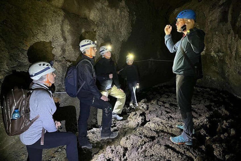 En gruppe mennesker i en hule, der bærer hjelme og rygsække, og bruger pandelamper. 4