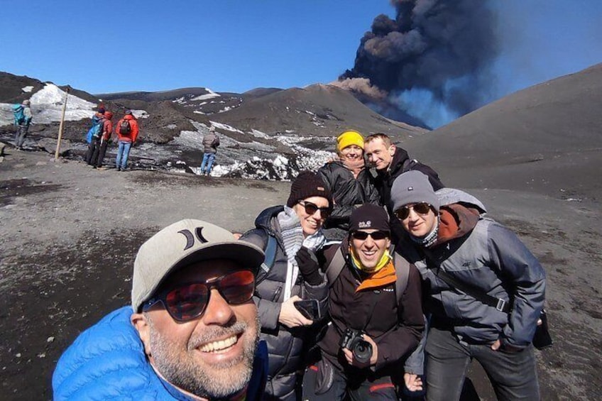 Un groupe de personnes se trouve dans un paysage enneigé, avec un volcan en arrière-plan. 1