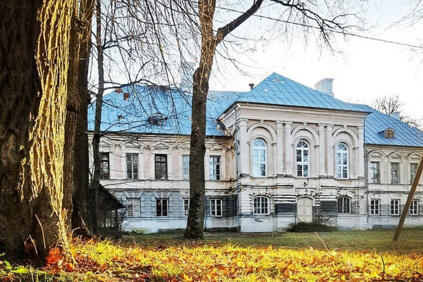 Un bâtiment de style classique, avec un toit bleu, entouré d’arbres et de feuilles d’automne. 4