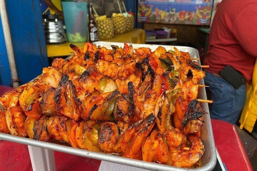 Ein Tablett mit gegrillten Garnelenspießen und Gemüse. 3