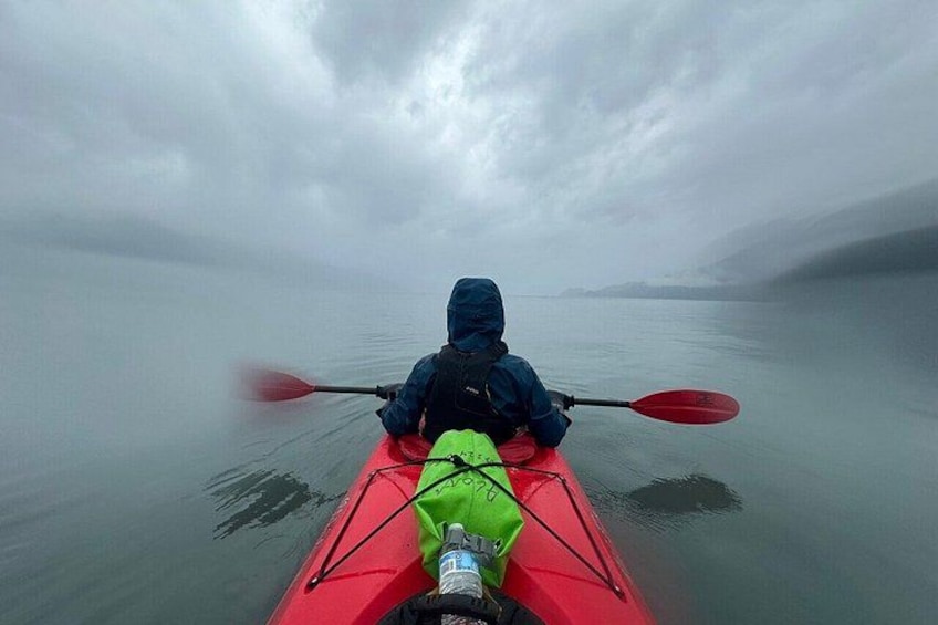 A person kayaking on a foggy lake. 3