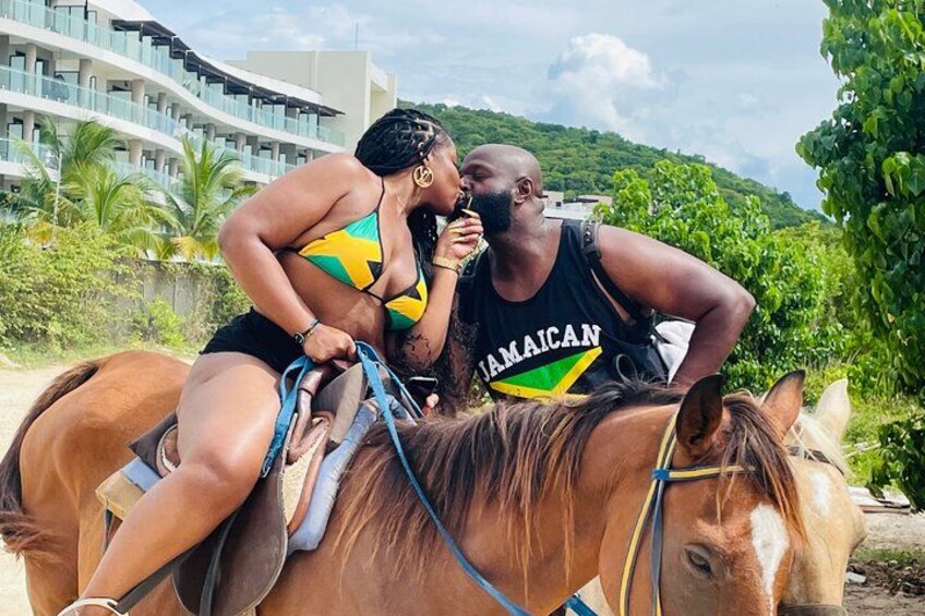 A person riding a horse on a beach with a hotel in the background. 3