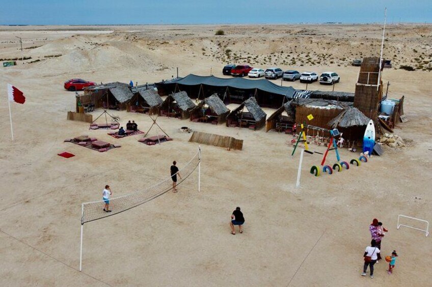 A beach with a volleyball net, tents, and a lifeguard tower. 4