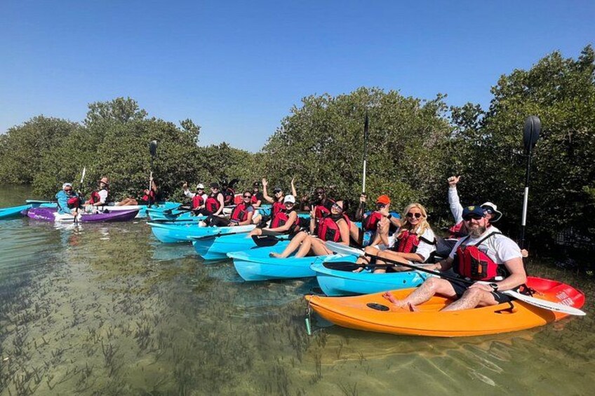 A group of people kayaking on a calm river surrounded by trees. 3