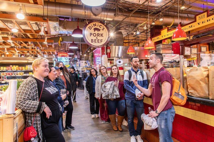 A group of people in a market with a sign that reads 'Tommy's Dine's Pork & Beef.' 2