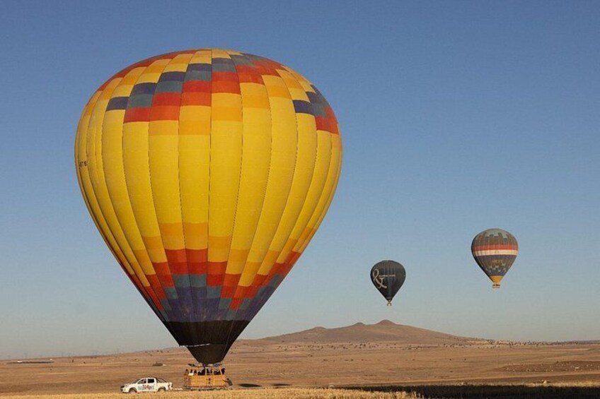 Trois montgolfières survolant un paysage désertique, avec une montagne en arrière-plan. 3
