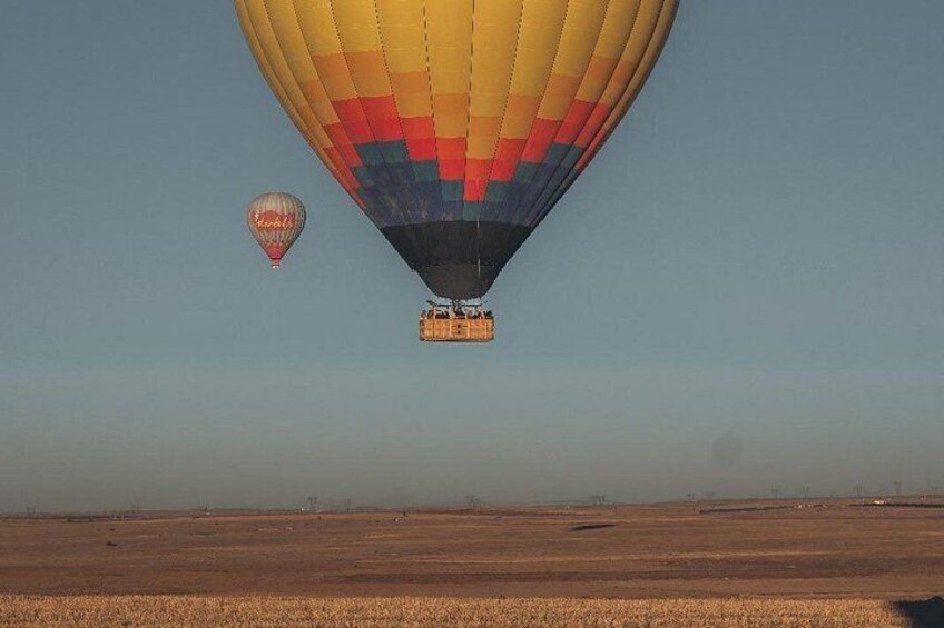 Deux montgolfières survolent un paysage plat, sous un ciel dégagé. 5