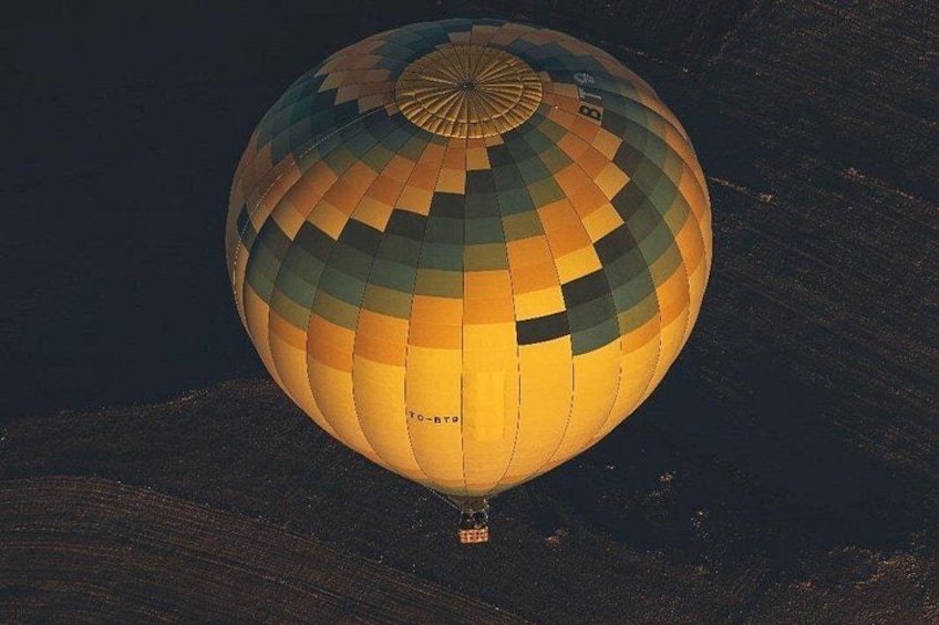Une montgolfière à motifs à carreaux, survolant un paysage montagneux. 4