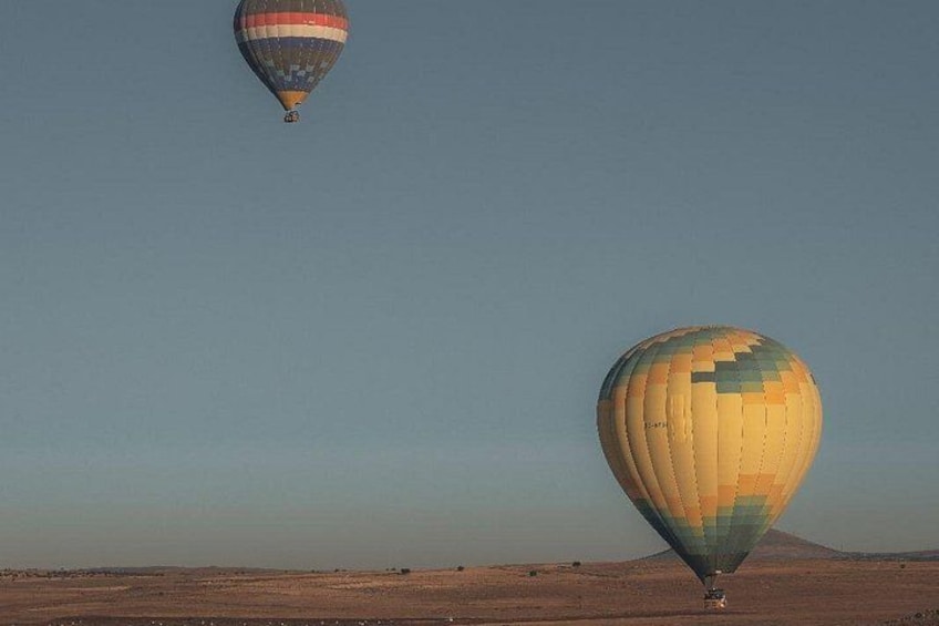 Deux montgolfières survolant un paysage désertique, sous un ciel dégagé. 2