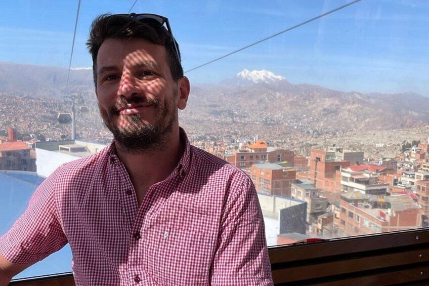 Una persona con camisa rojo y blanco a cuadros, un paisaje montañoso y una vista urbana con edificios. 2