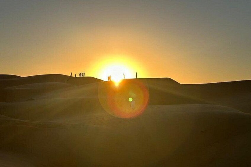 Wüstenlandschaft mit Sanddünen und untergehender Sonne im Hintergrund. 3