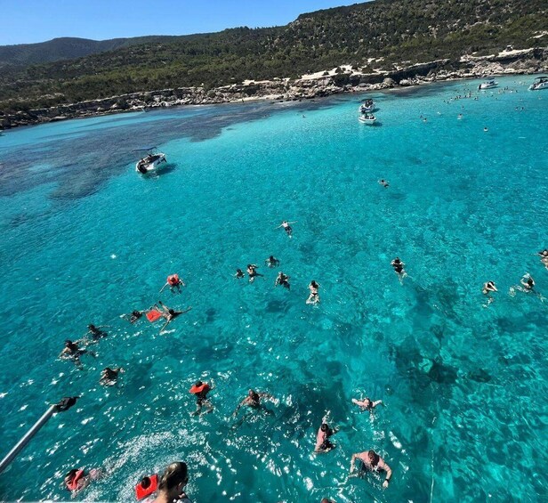 Un groupe de personnes fait de la plongée avec tuba dans une mer d’un bleu limpide, avec des bateaux en arrière-plan. 5