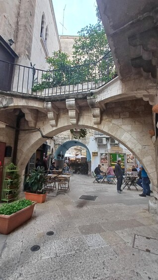 Un espace café en plein air agrémenté d’arches en pierre, de plantes en pot et de personnes qui prennent leur repas. 5