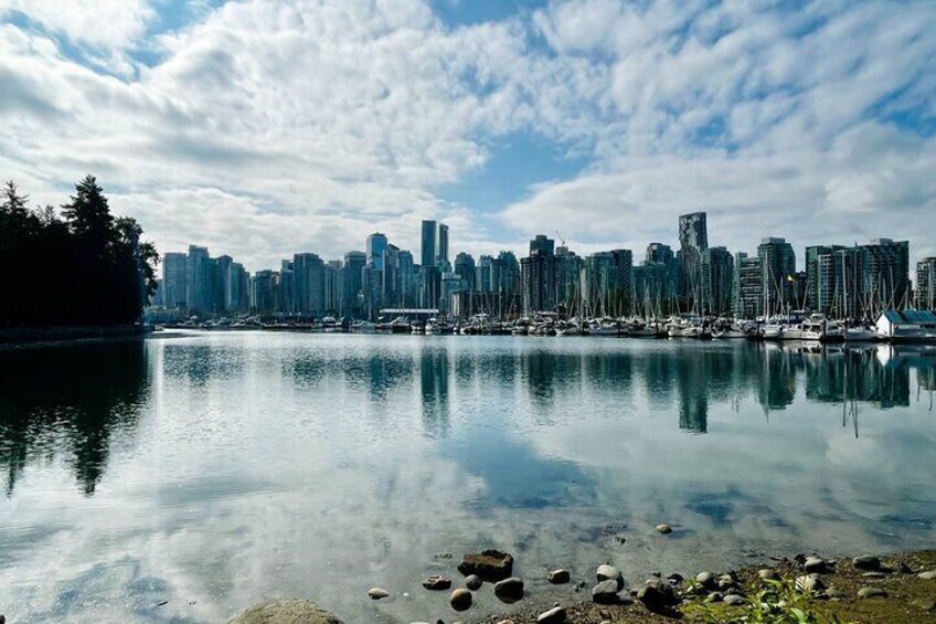 A calm lake reflecting a city skyline with high-rise buildings and a clear sky. 2