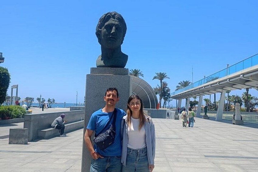 A sculpture of a man's head on a pedestal, a clear blue sky, and a pedestrian walkway. 2